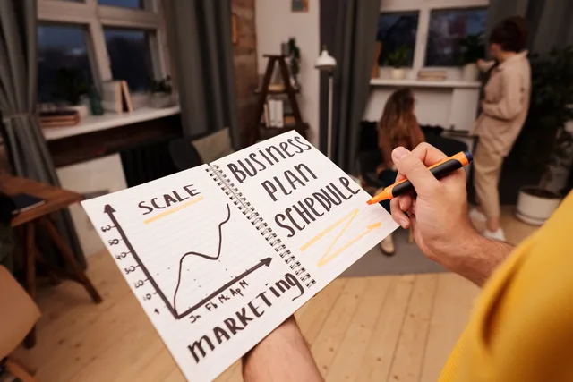 Person holding a notebook with planning details and graph for business strategy indoors. Skalering af SMV'er: kapacitet, organisering og likviditet